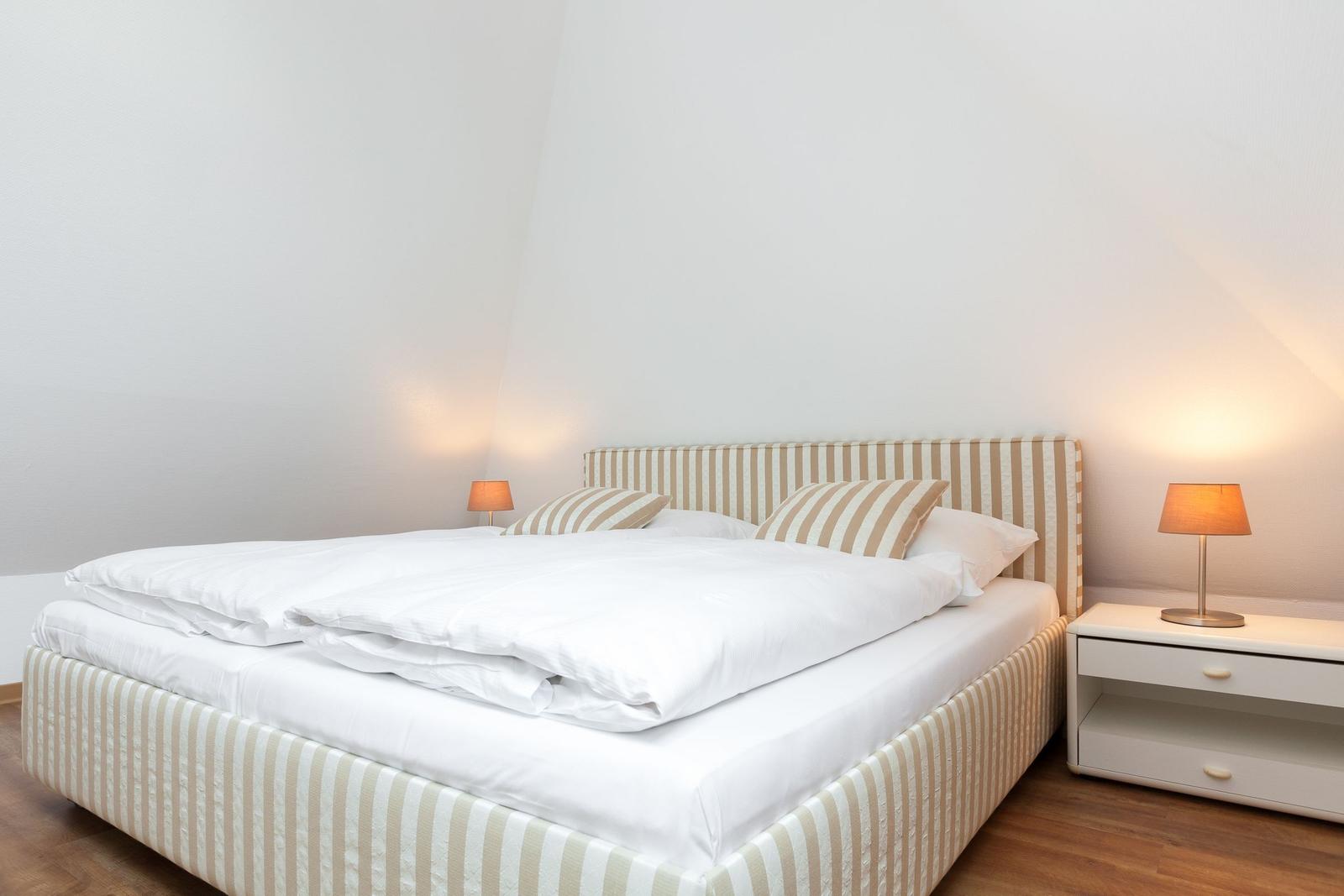 Bedroom with bed, nightstand, and lamps.