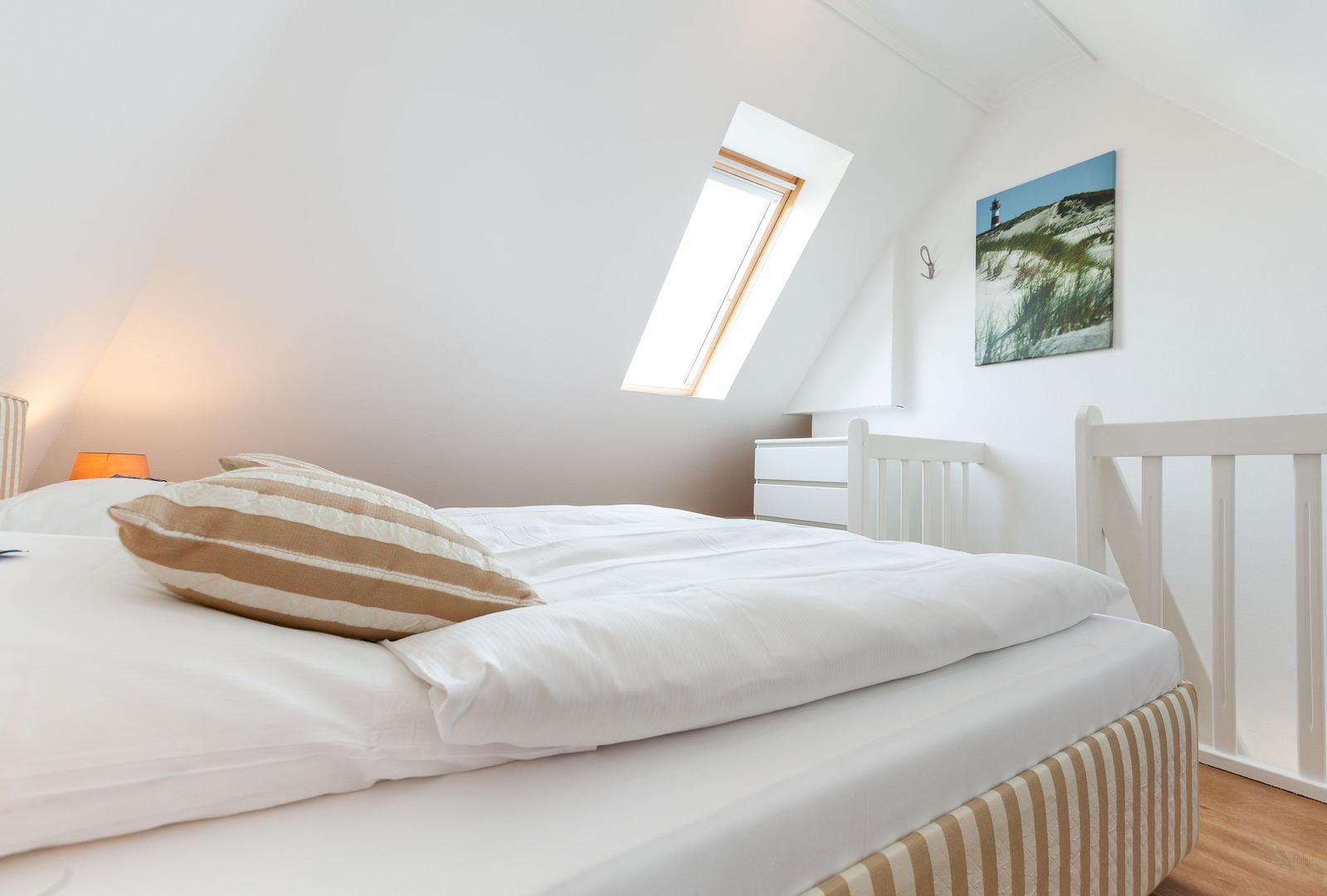 Bedroom with skylight, bed and wall picture