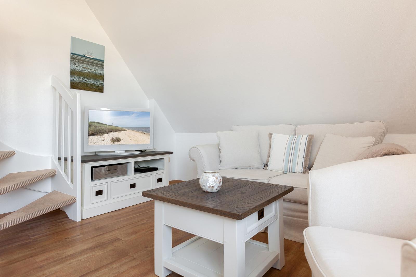 Living room with sofa, TV, and table under sloped ceiling