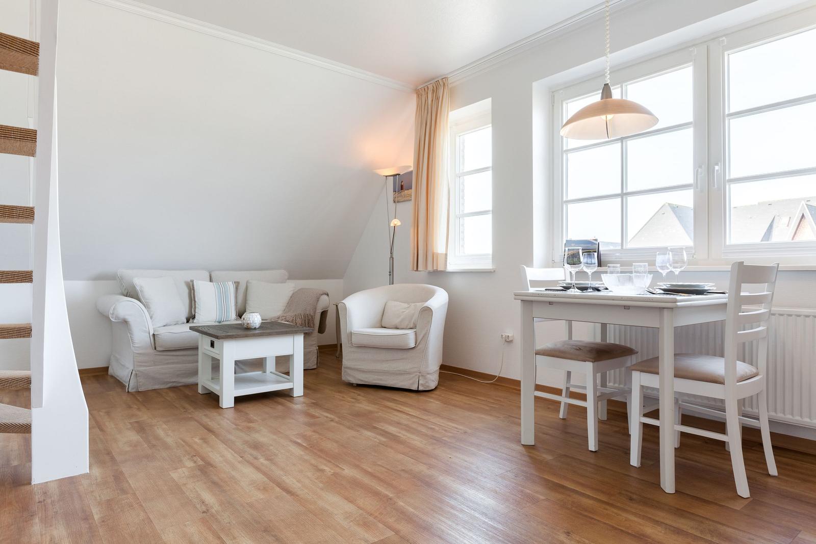 Living and dining area with sofa, chair, table, and windows.