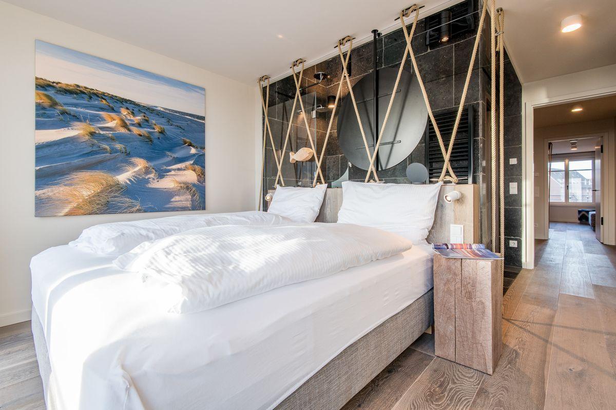 Schlafzimmer mit Bett, Wandbild und Holzboden
