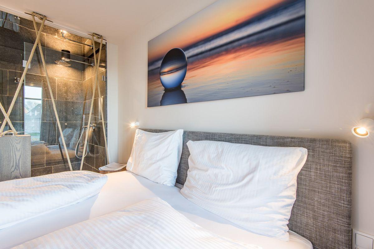 Schlafzimmer mit Doppelbett, Dusche und Wandbild.