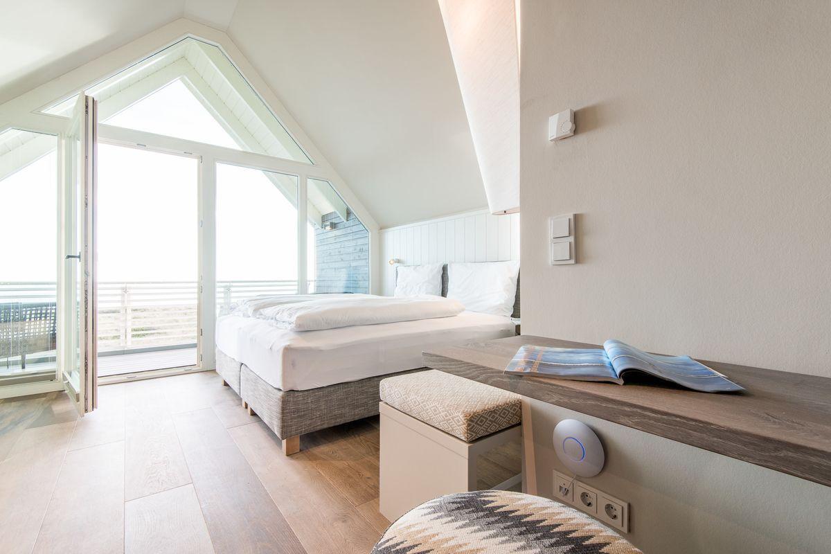 Schlafzimmer mit Doppelbett, Terrassentür und Schreibtisch.