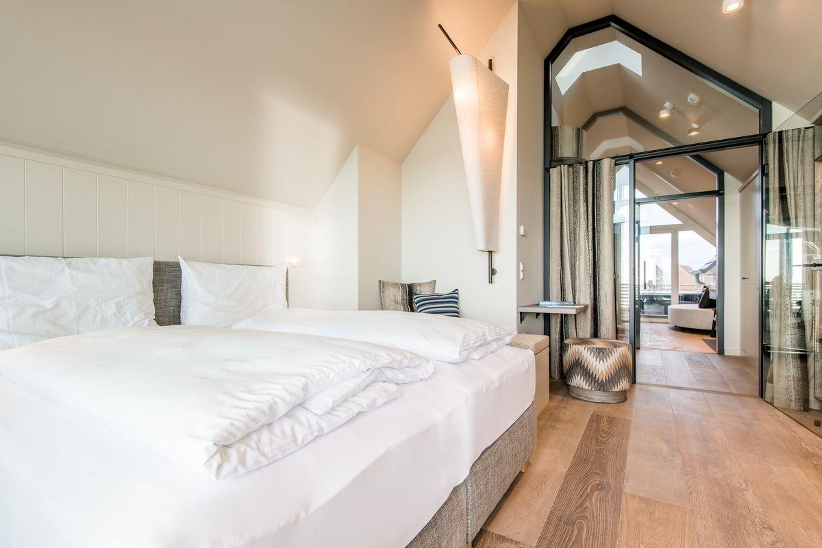 Schlafzimmer mit Doppelbett, Holzboden und Blick in Wohnbereich.