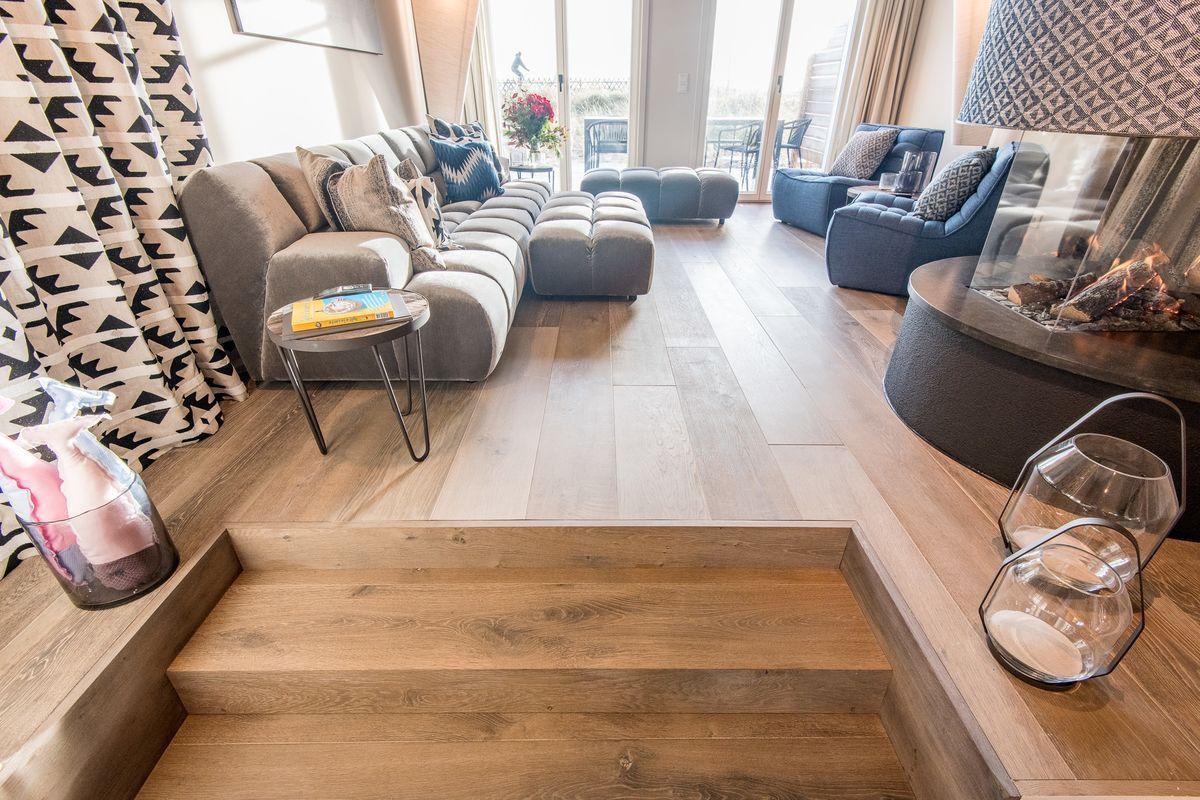 Eingangsbereich mit Holztreppe, Sofa, Kamin und Terrasse.