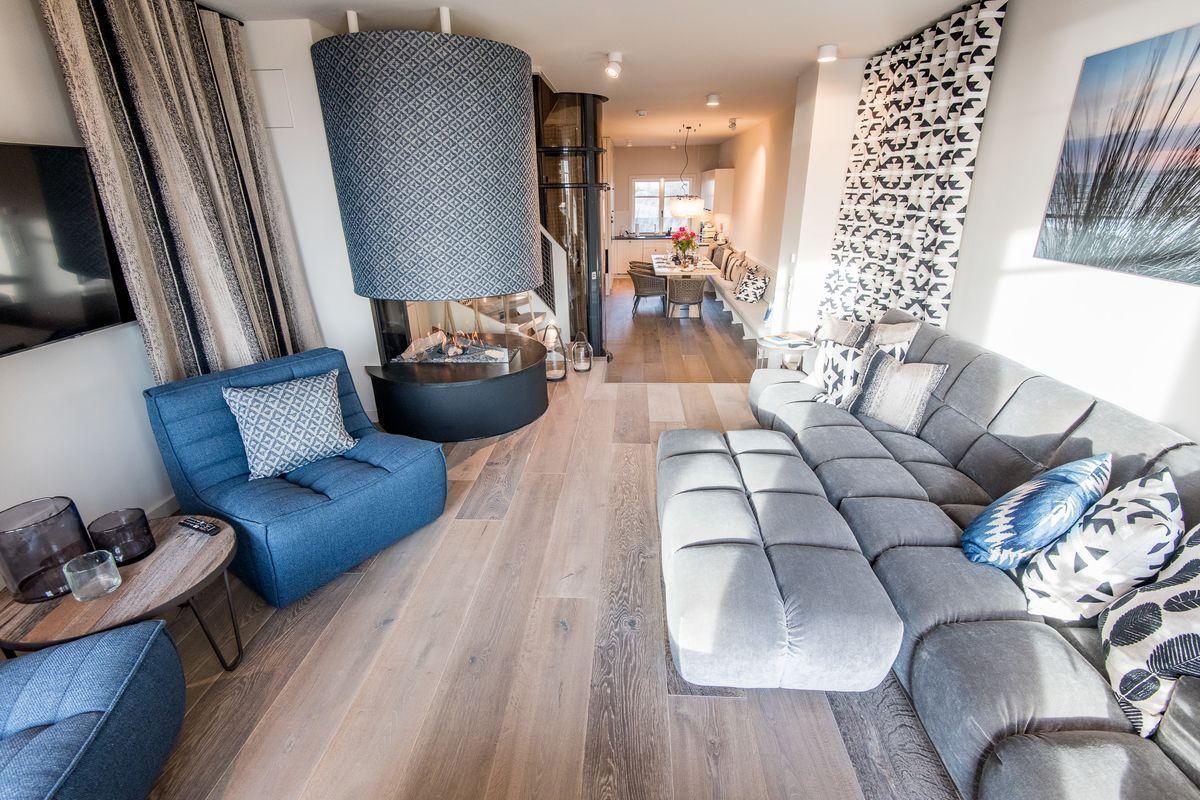Wohnzimmer mit grauem Sofa, blauem Sessel und Kamin