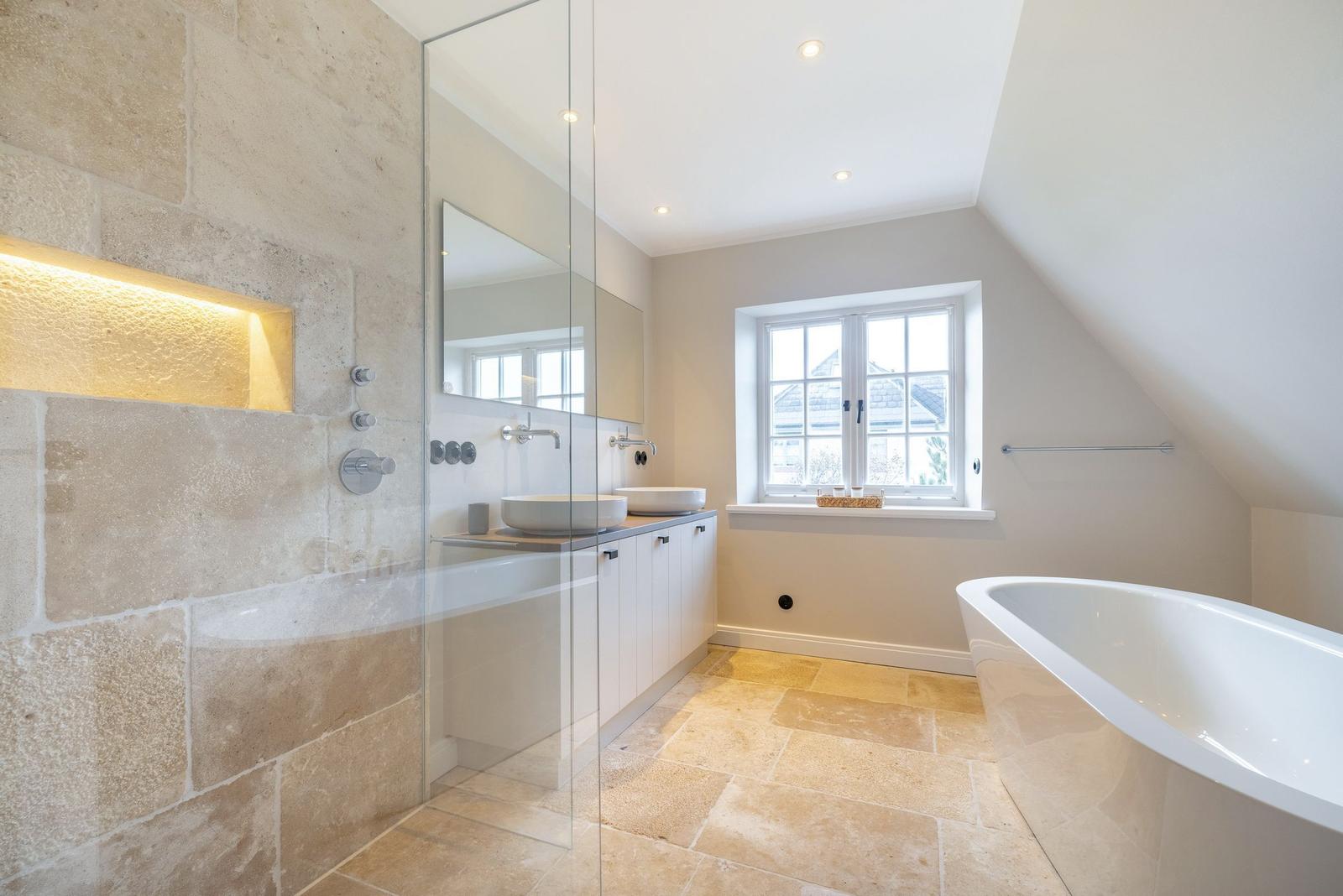 Dusche mit Steinwand, Waschbecken und freistehende Badewanne.