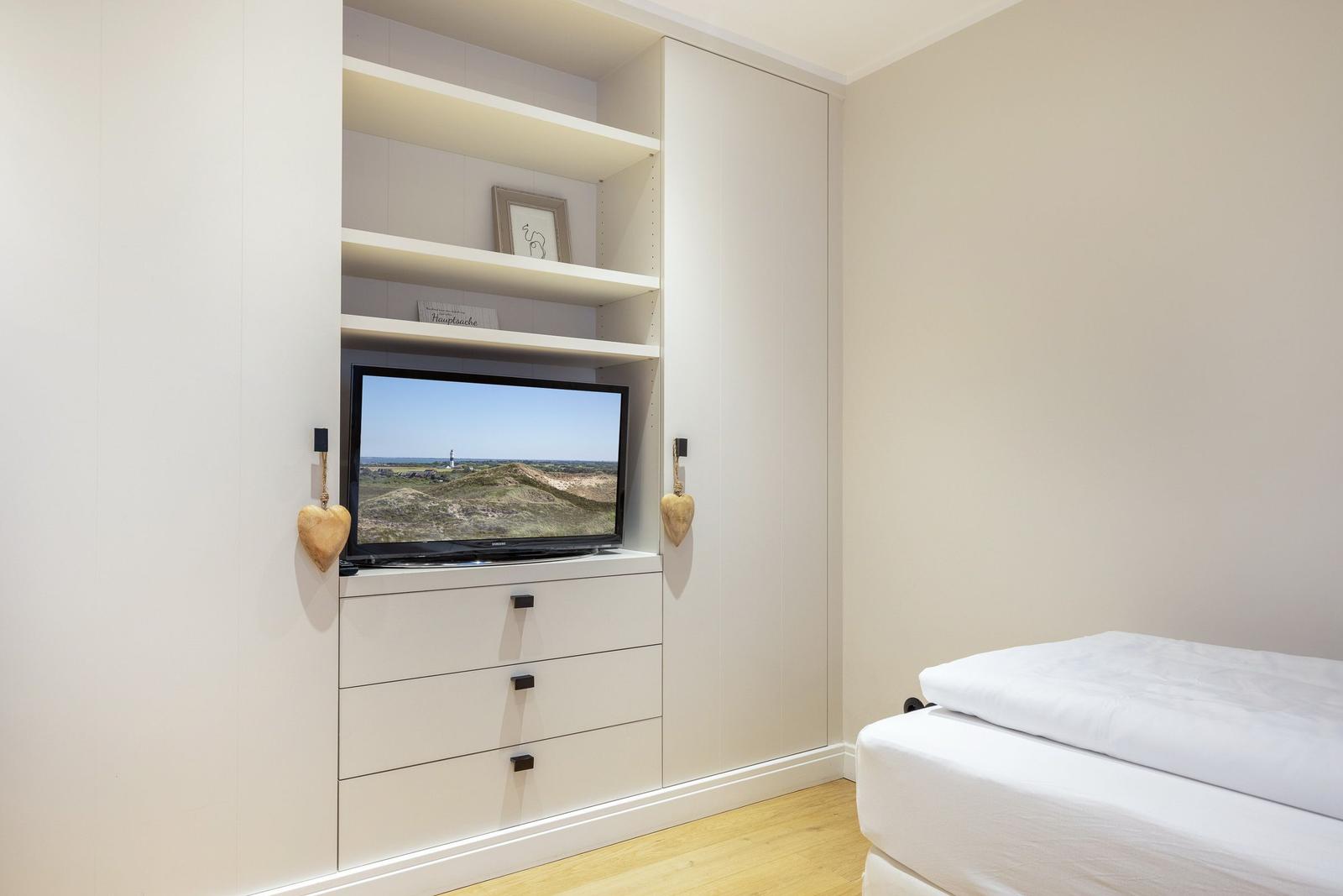 Schlafzimmer mit Bett, TV und Schrank