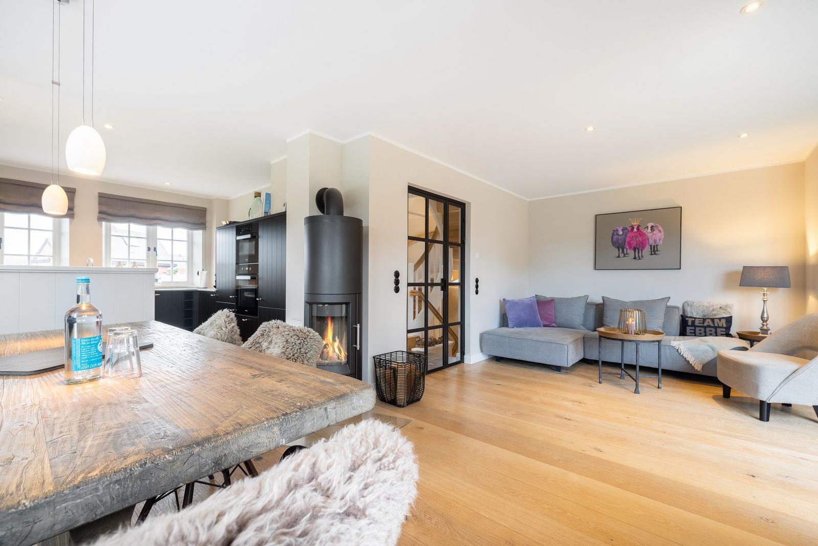 Wohn- und Essbereich mit Holzboden, Kamin und Sofa.
