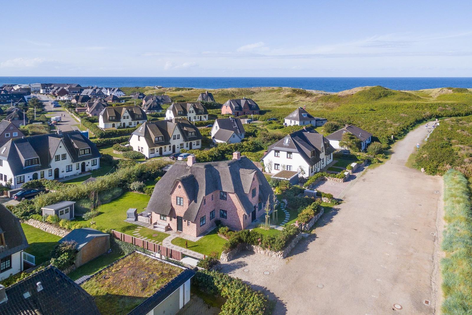 Haus mit Dach und Garten, umgeben von Grünflächen und Meer