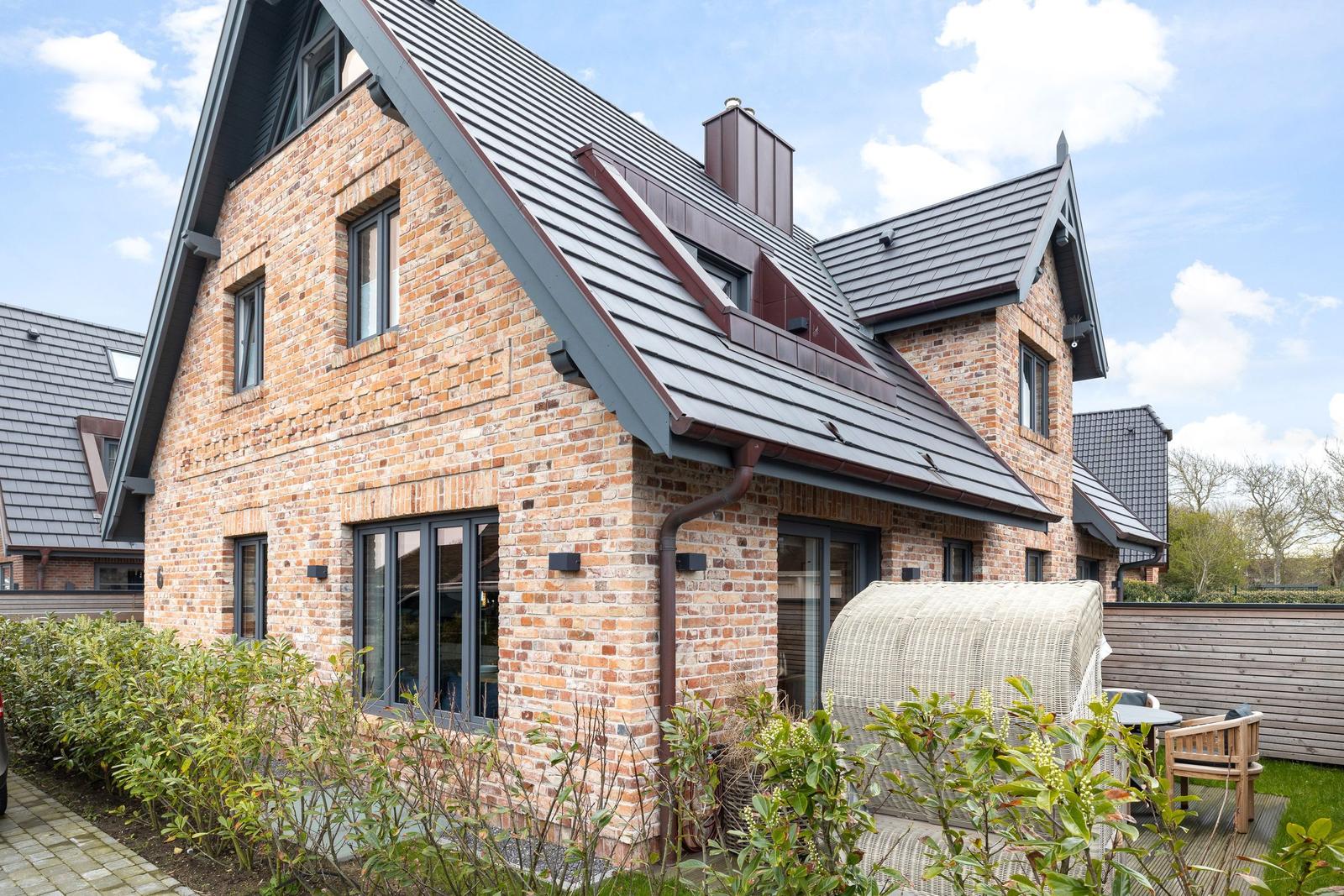Haus mit Backsteinfassade und Holzterrasse im Garten