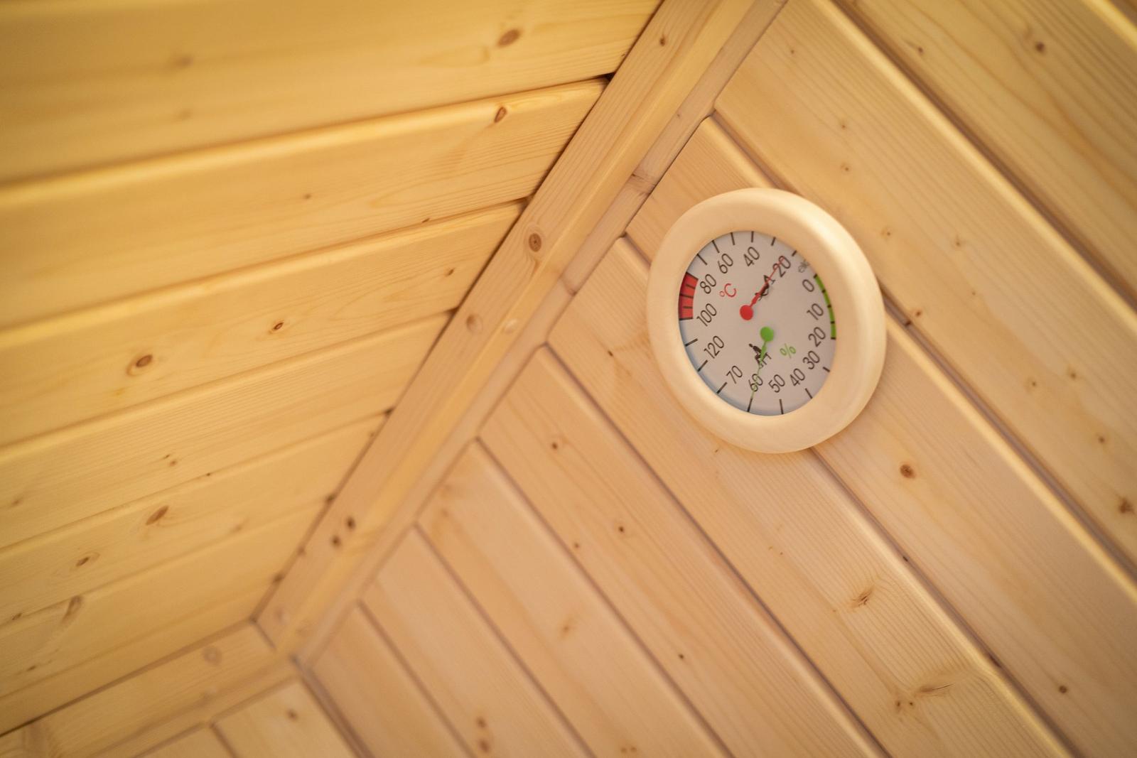 Sauna mit Holzwand und Temperatur-Feuchtigkeitsmessgerät an der Wand.
