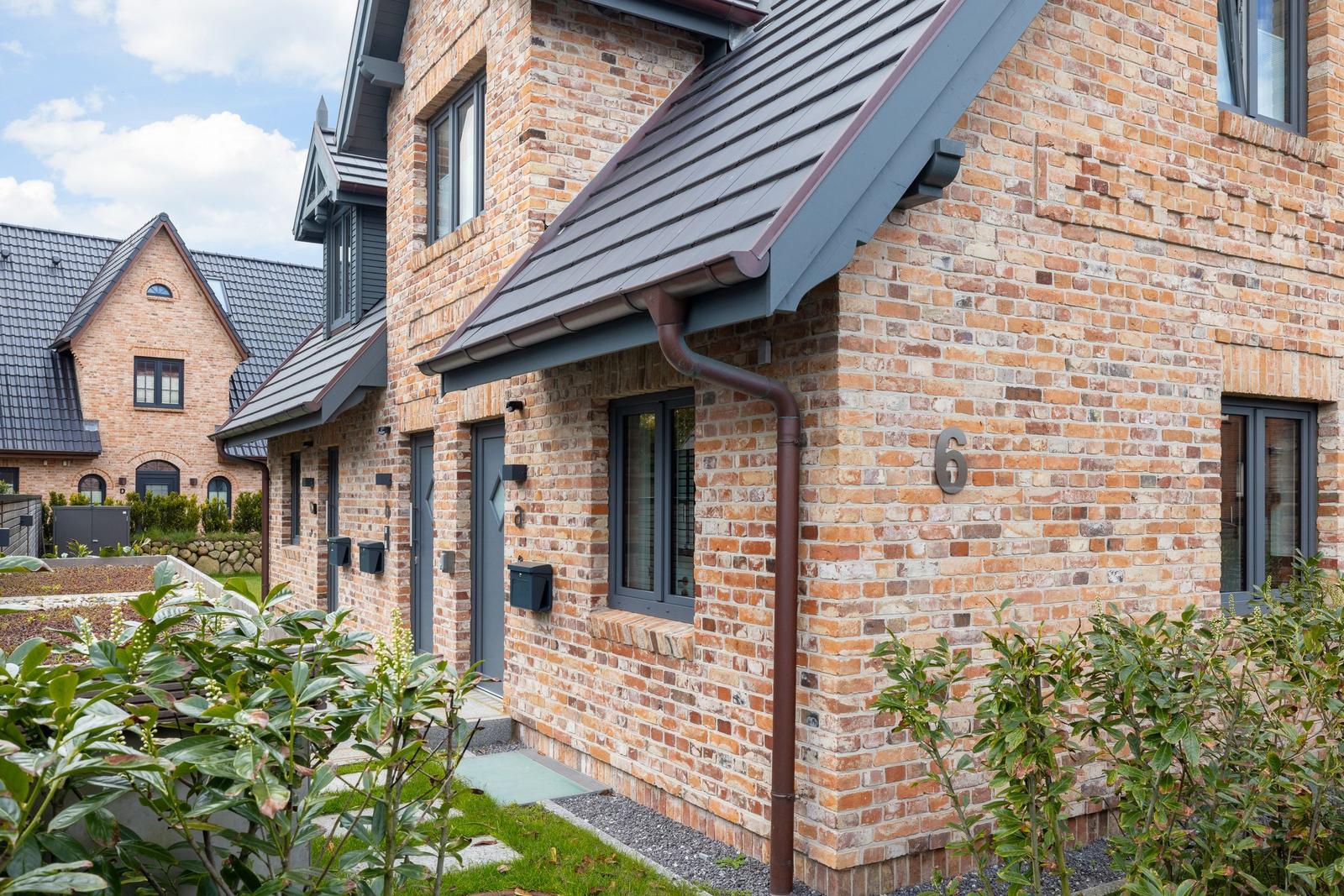 Haus mit Backsteinfassade und grauem Dach. Nummer 6 an der Wand.