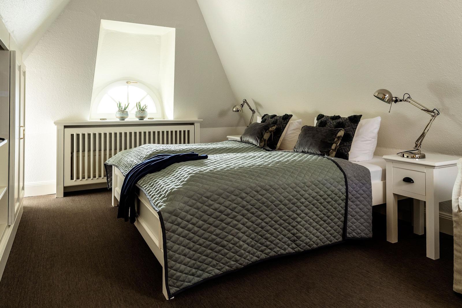 Bedroom with sloped ceiling, window, bed, and nightstand.