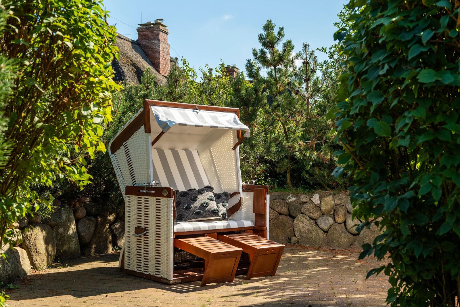 Hanging chair with awning and cushions on paved courtyard.