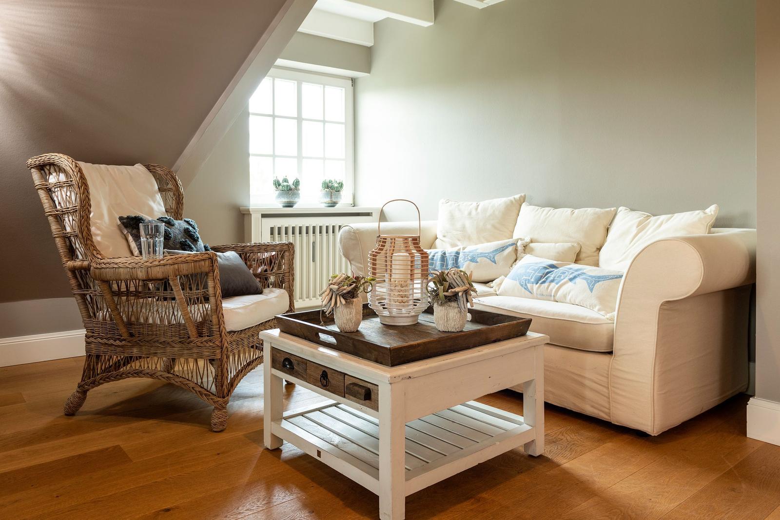 Living room with armchair, sofa, and table under sloped ceiling.