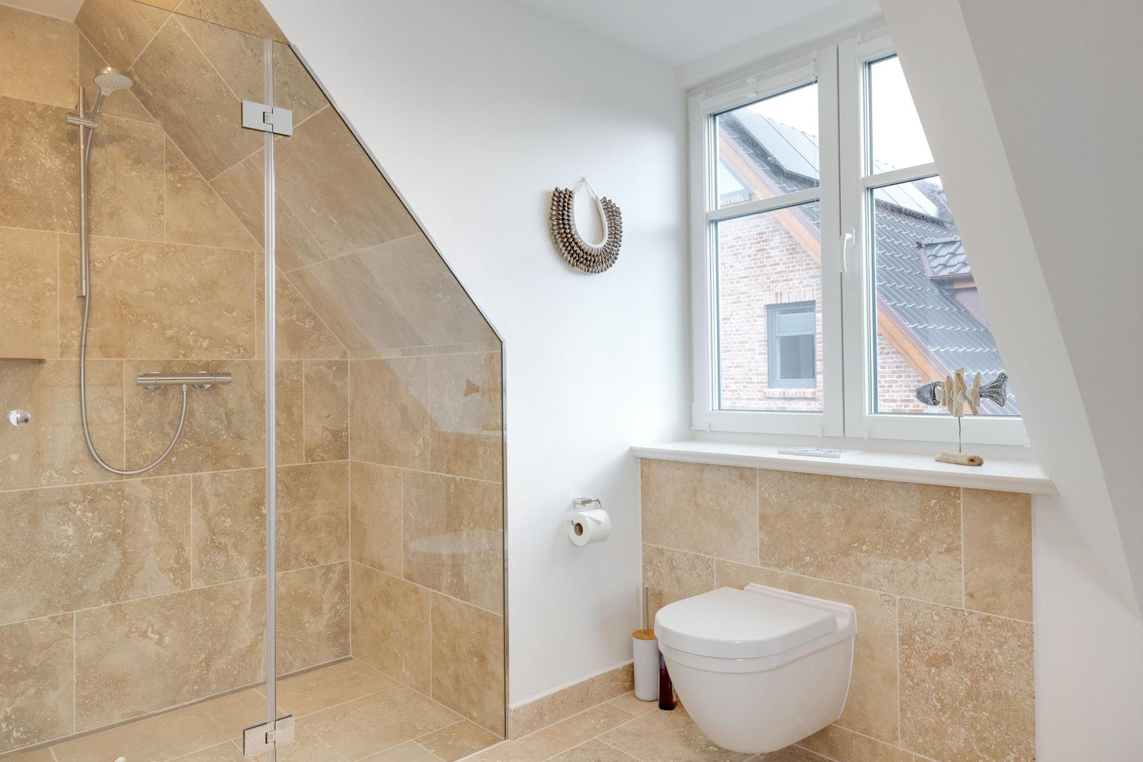 Dusche mit Glaswand, Toilette und Fenster mit Blick auf Dach