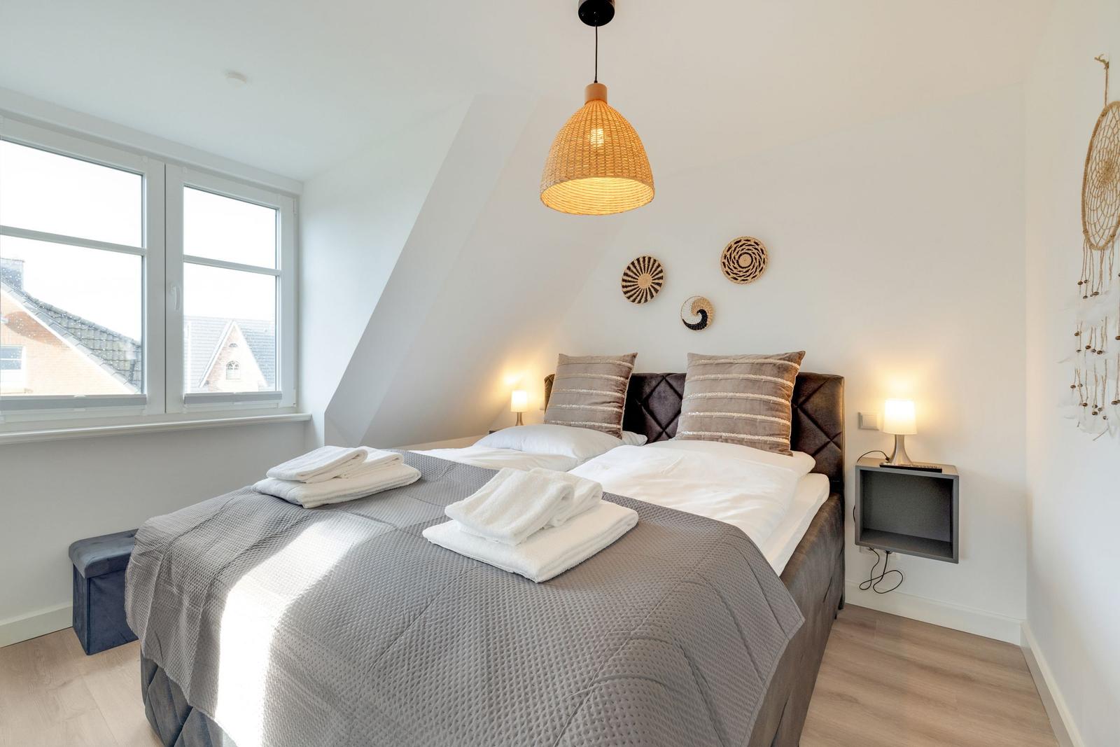 Schlafzimmer mit Dachschräge, Bett, Fenster und Lampe.