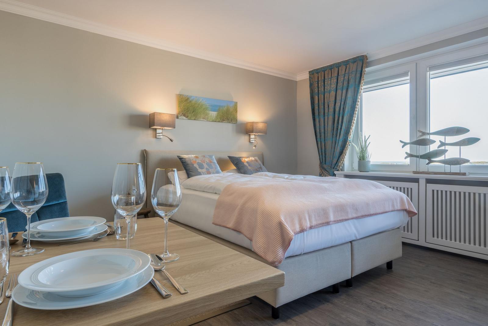 Schlafzimmer mit Bett, Tisch und Fenster