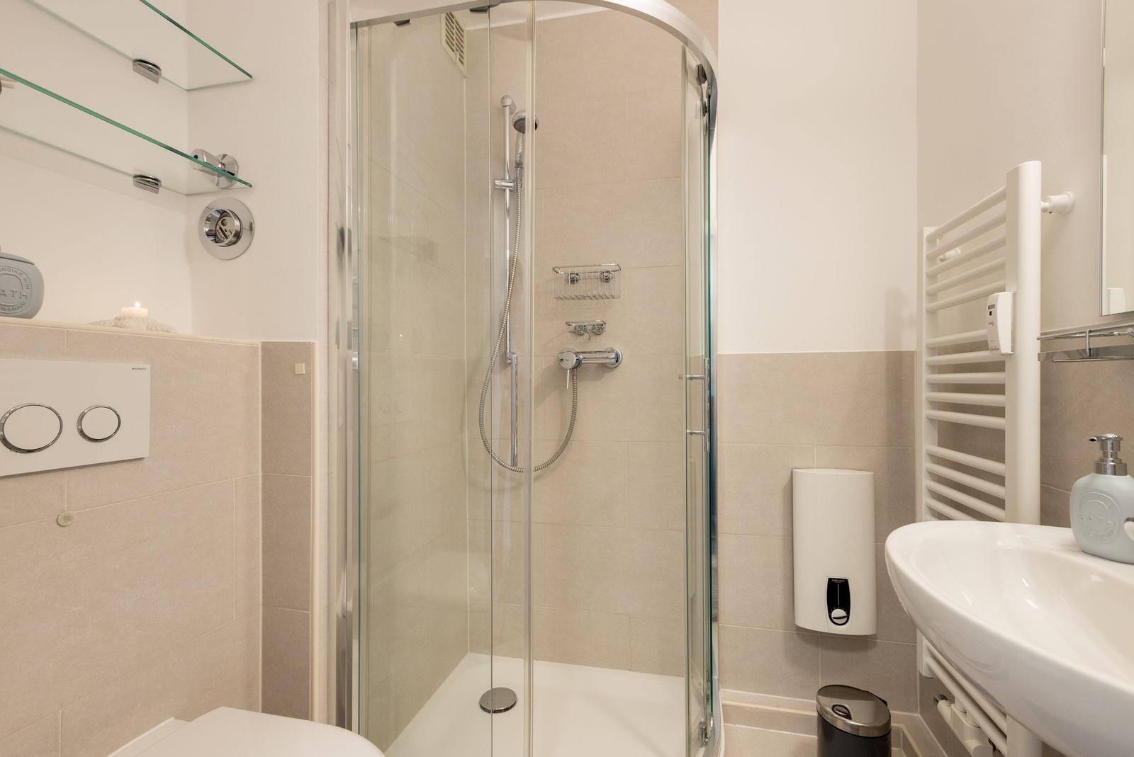 Badezimmer mit Dusche, Waschbecken und Heizkörper