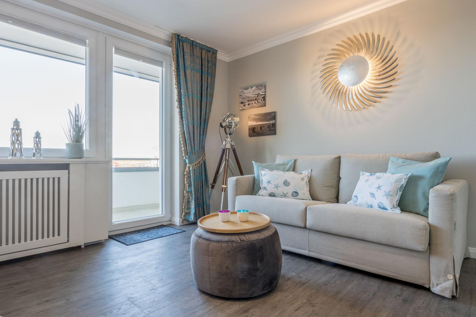 Wohnzimmer mit Sofa, Tisch und Fenster zur Terrasse.