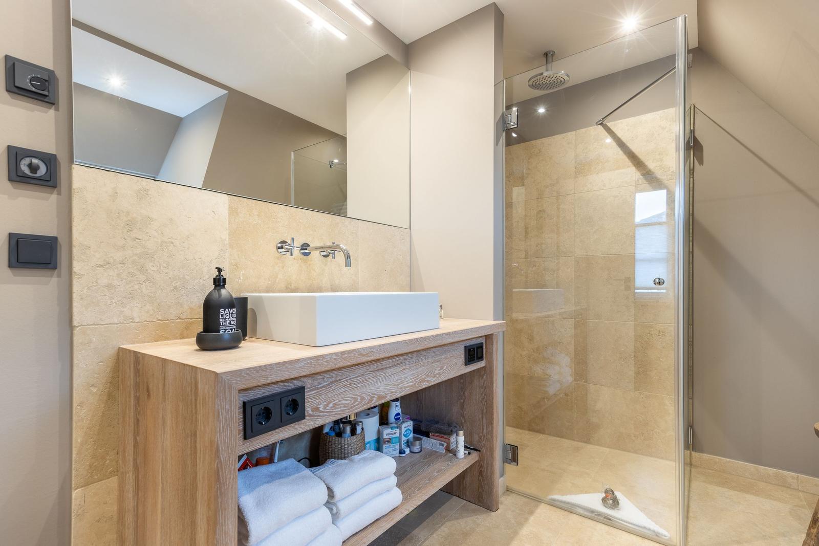 Badezimmer mit Dusche, Waschtisch und Spiegel