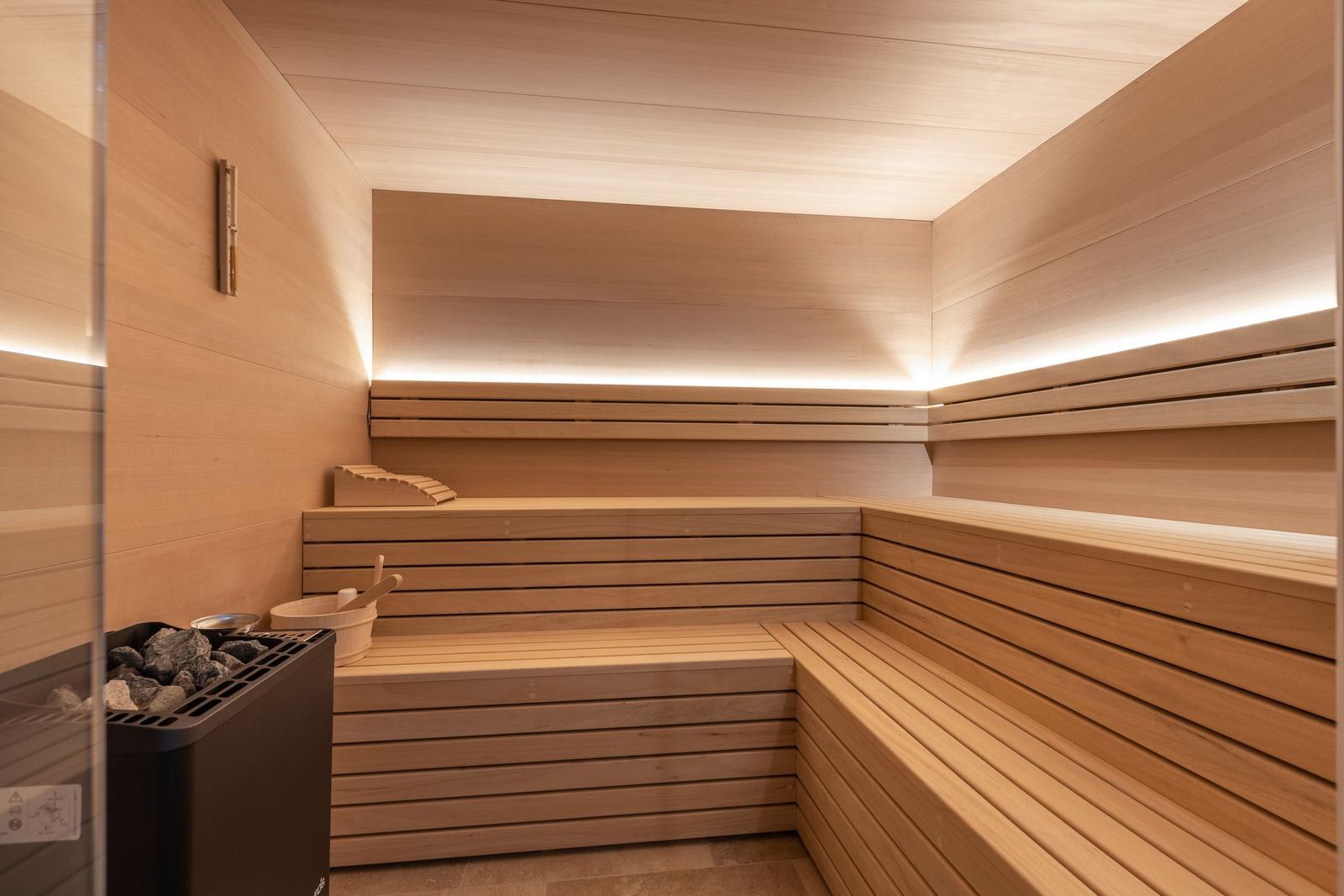 Sauna mit Holzbanken und Beleuchtung an der Wand