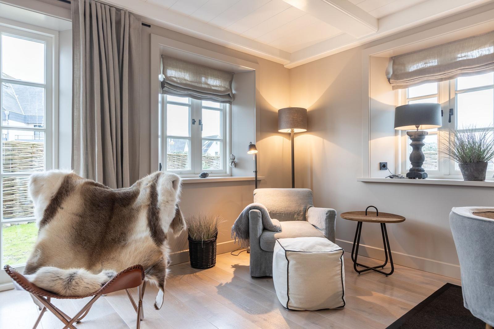 Wohnzimmer mit Sessel, Stuhl mit Fell, Tisch und Lampen.