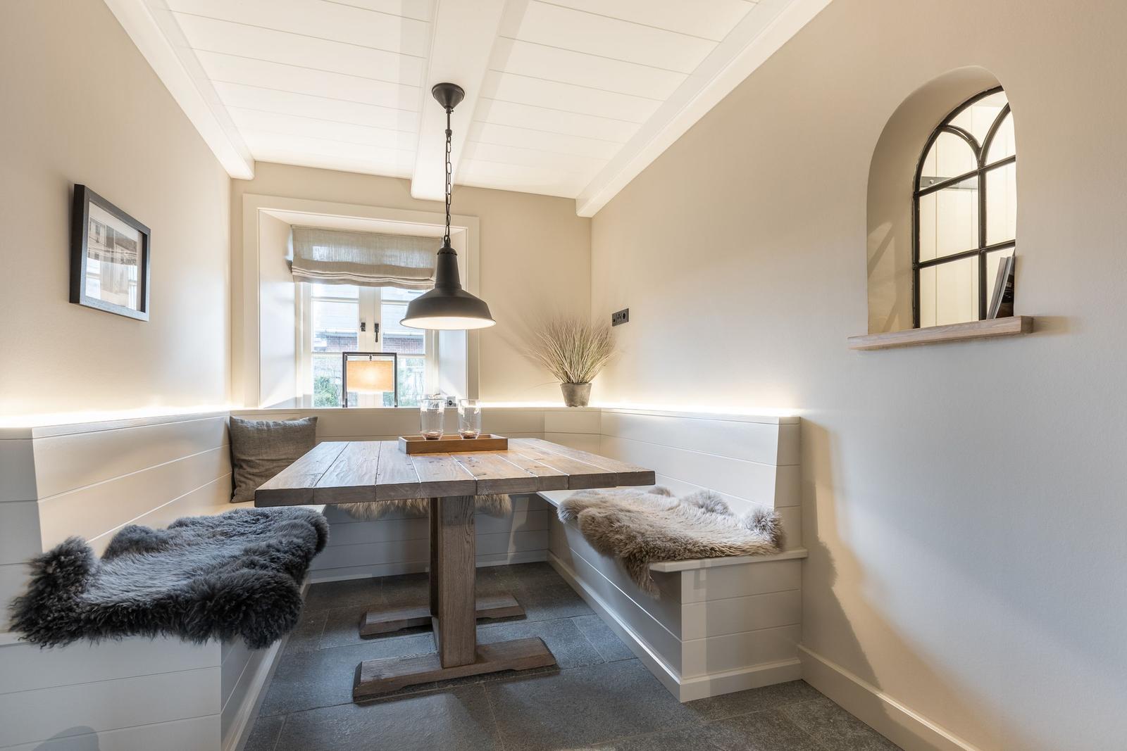 Essbereich mit Holztisch, Sitzbänken und Fenster
