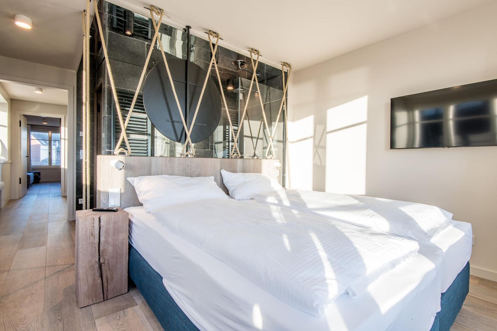 Schlafzimmer mit Doppelbett, Holzboden und Wandspiegel