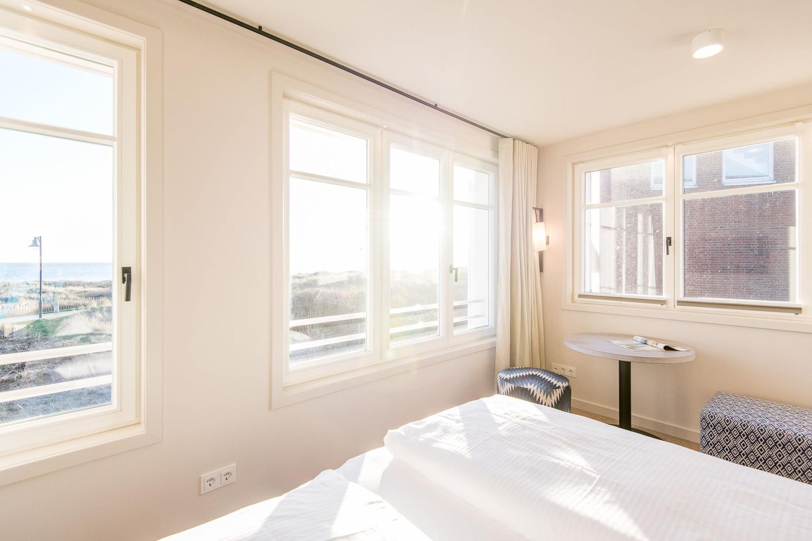 Schlafzimmer mit Blick aufs Meer und Fenster mit Vorhängen.