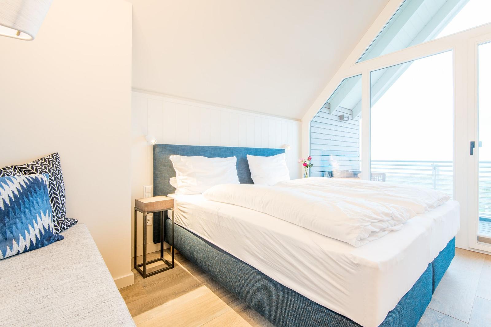 Schlafzimmer mit Doppelbett, Balkon und moderner Einrichtung.