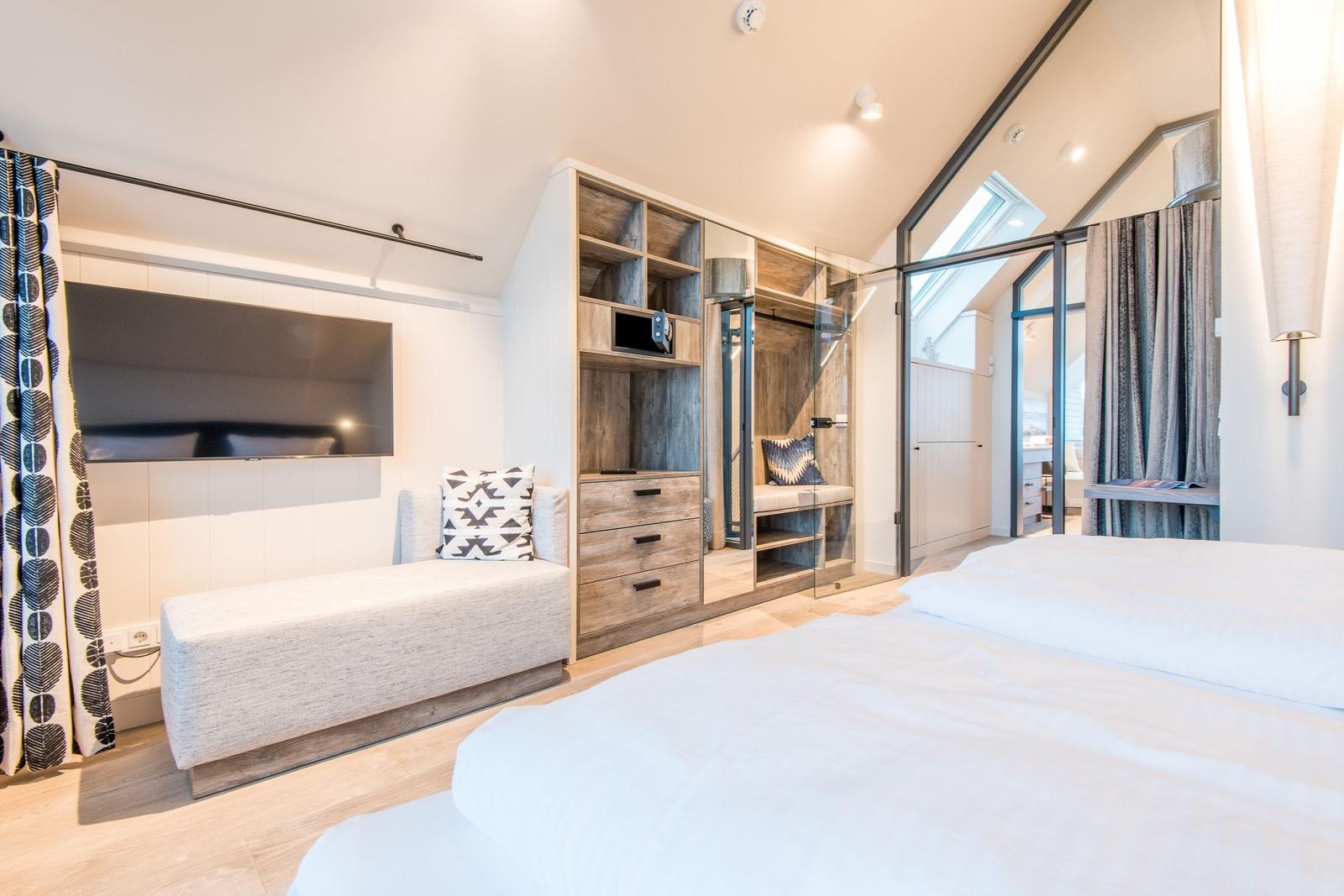 Schlafzimmer mit Doppelbett, Kleiderschrank und Fernseher.