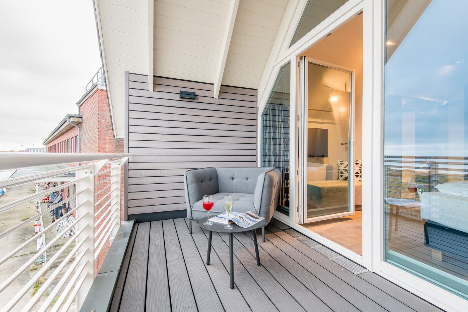 Terrasse mit Sitzgelegenheit und Blick ins Innere. Holzdecke und Glaswände.