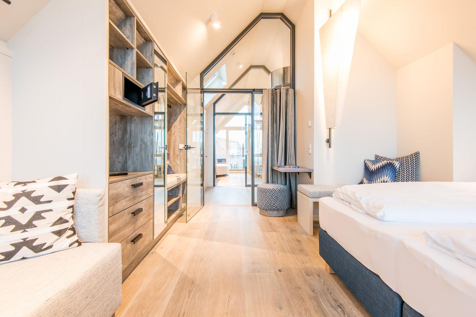 Schlafzimmer mit Bett, Schrank und Glaswand zur Terrasse
