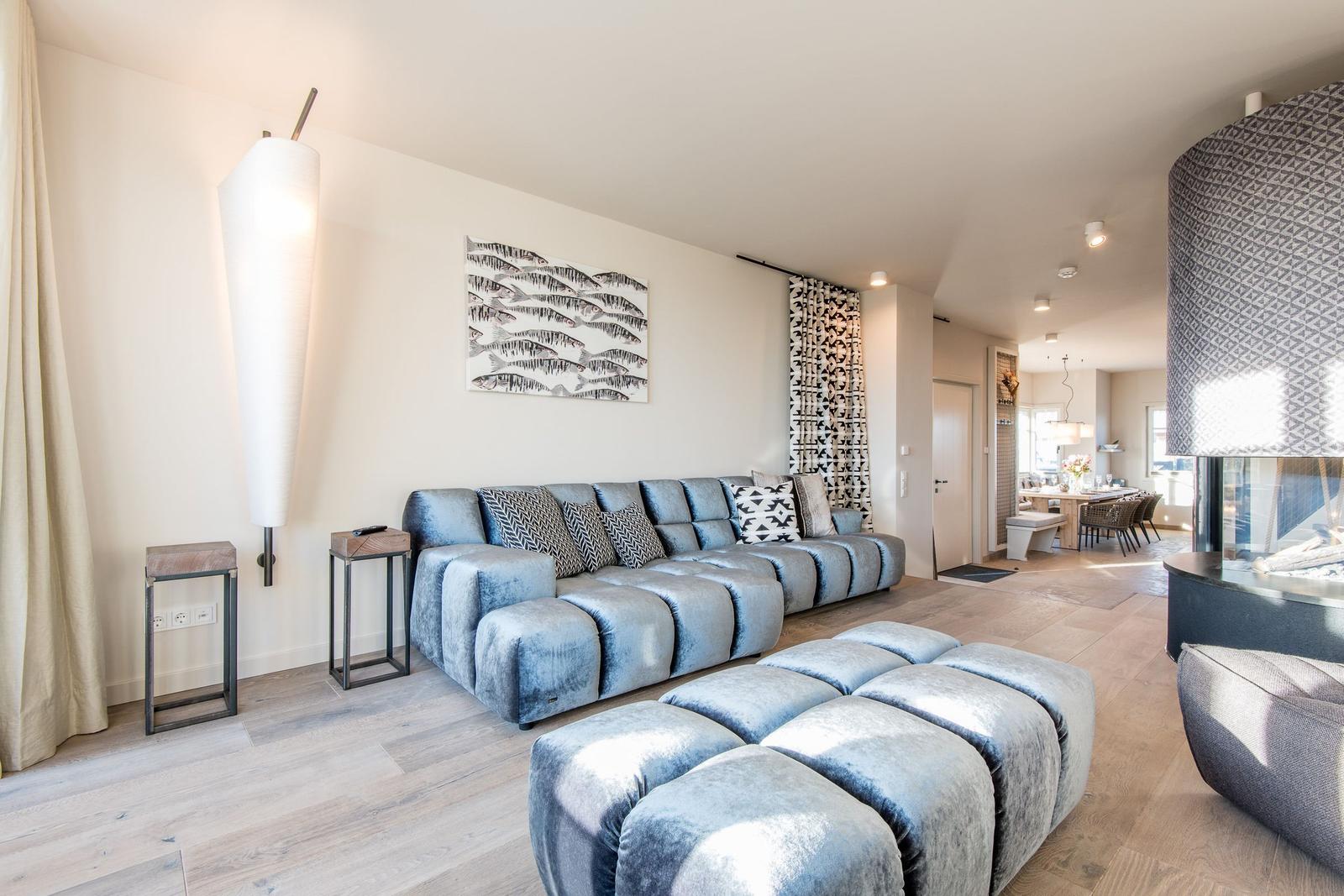 Wohnzimmer mit blauem Sofa und Fußhocker, moderner Beleuchtung und Wanddekoration.