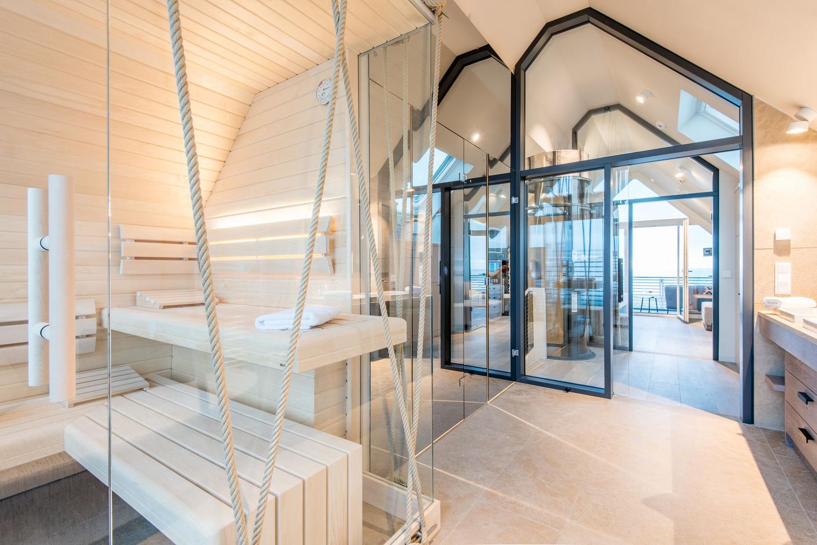 Sauna mit Seilbänken und Glasabtrennung. Blick auf Wohnbereich mit Balkon.