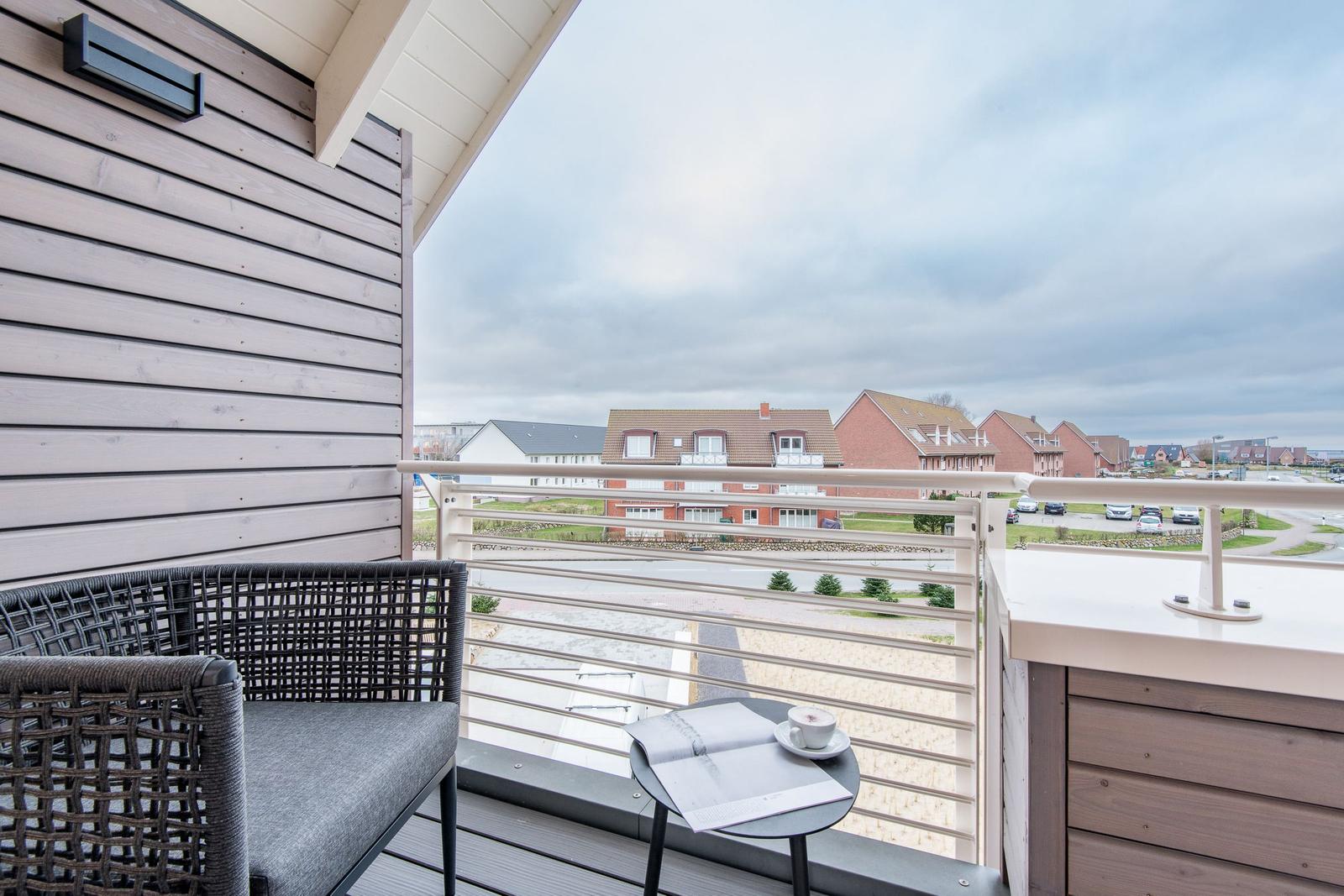 Terrasse mit Stuhl und Tisch, Blick auf Wohnhäuser und Straße.