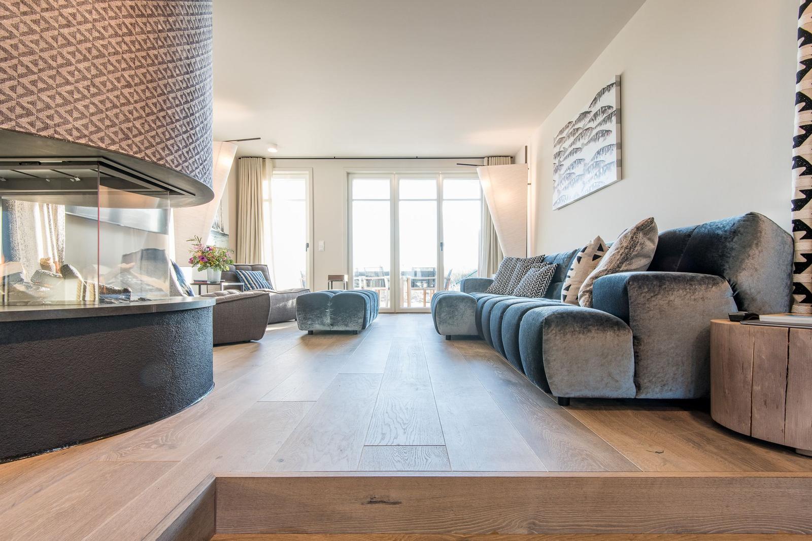 Wohnzimmer mit Sofa, Kamin und Holzboden