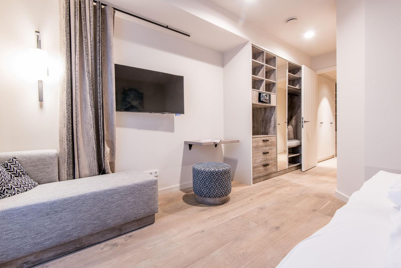 Schlafzimmer mit Bett, Sofa, TV und Kleiderschrank.