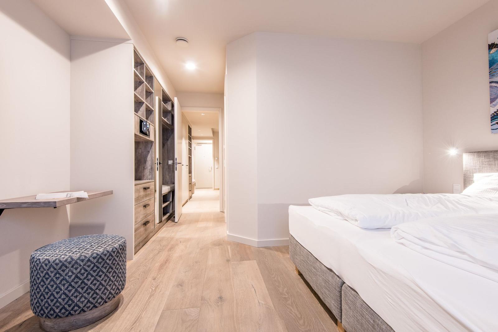 Schlafzimmer mit Bett, Kleiderschrank und Holzboden.