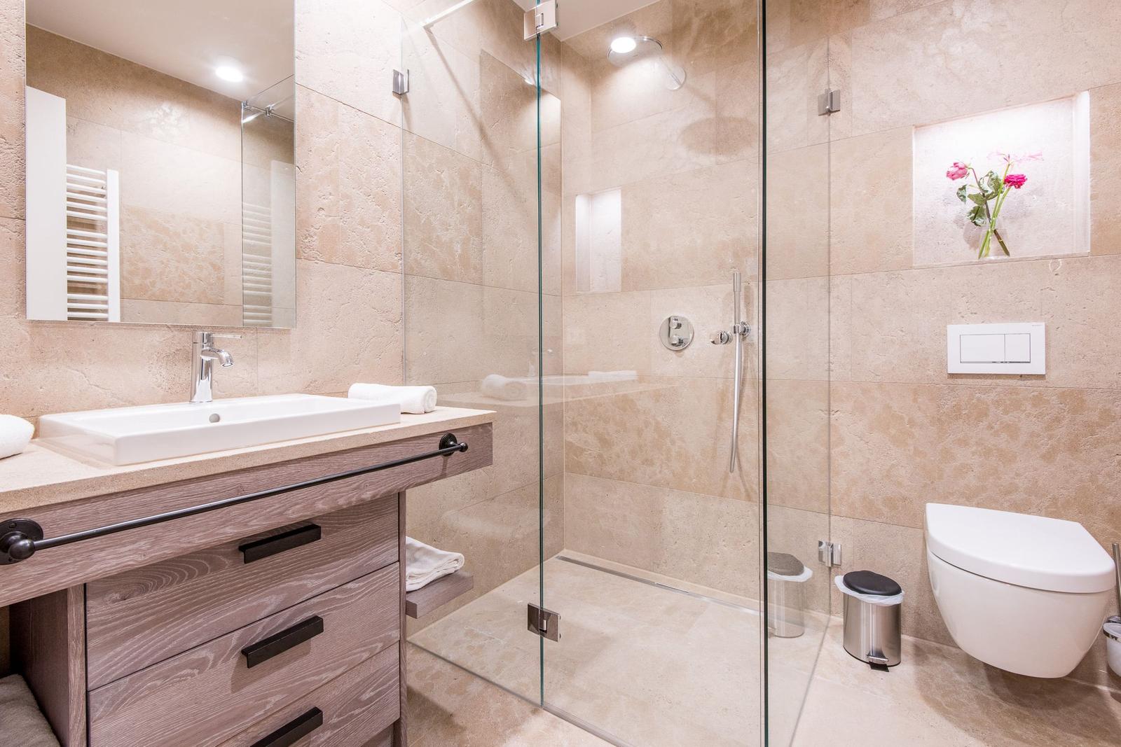 Bad mit Dusche, Waschbecken und Toilette. Steinwand und Holzschrank.