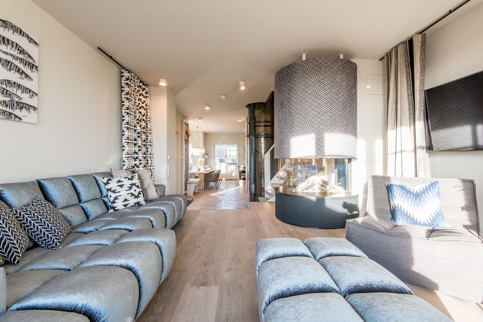 Wohnzimmer mit Sofa, Sessel und Kamin. Holzboden und moderne Einrichtung.