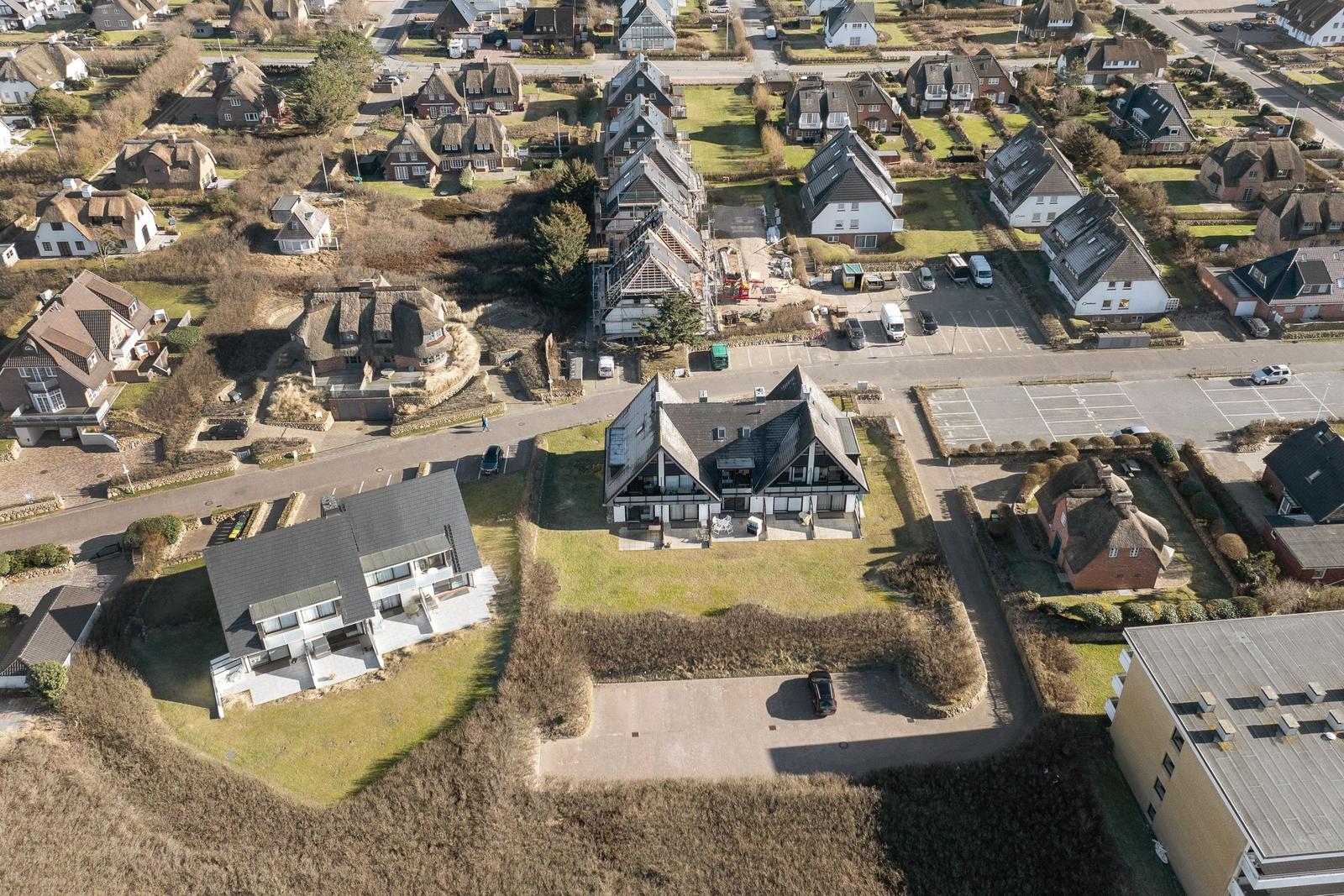 Aerial view of houses with roofs and green areas in a residential area.