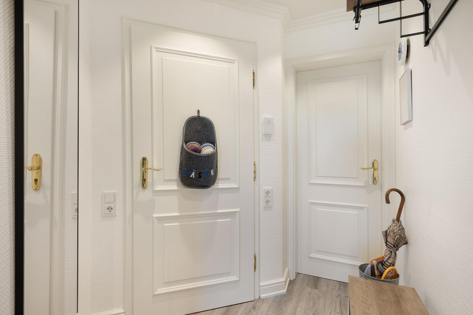 Entrance area with white doors and shoe holder on the door.