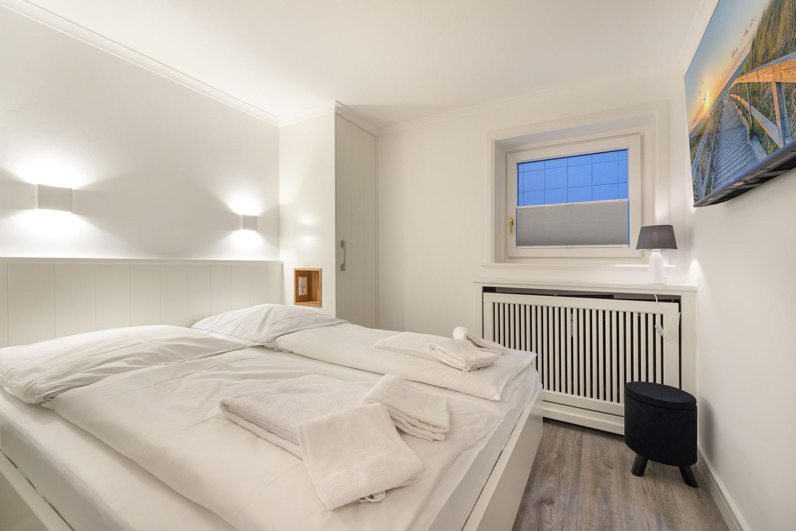 Bedroom with double bed, window, and wall picture.