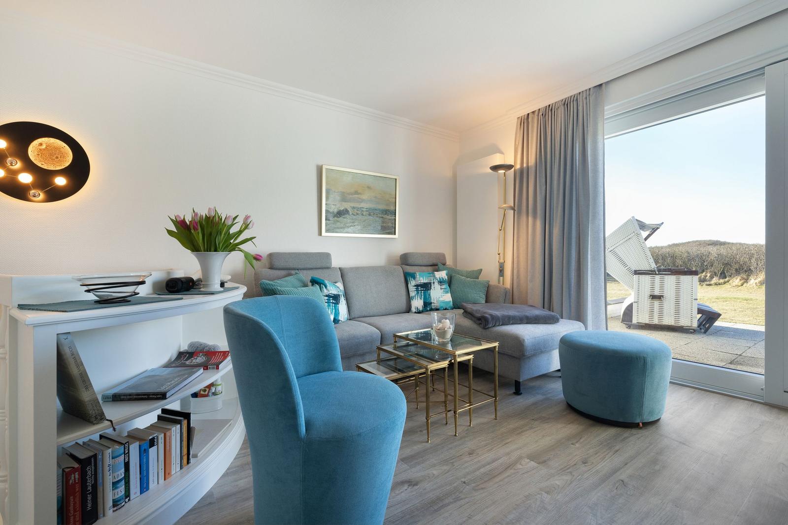 Living room with sofa, blue seating, and view of terrace.