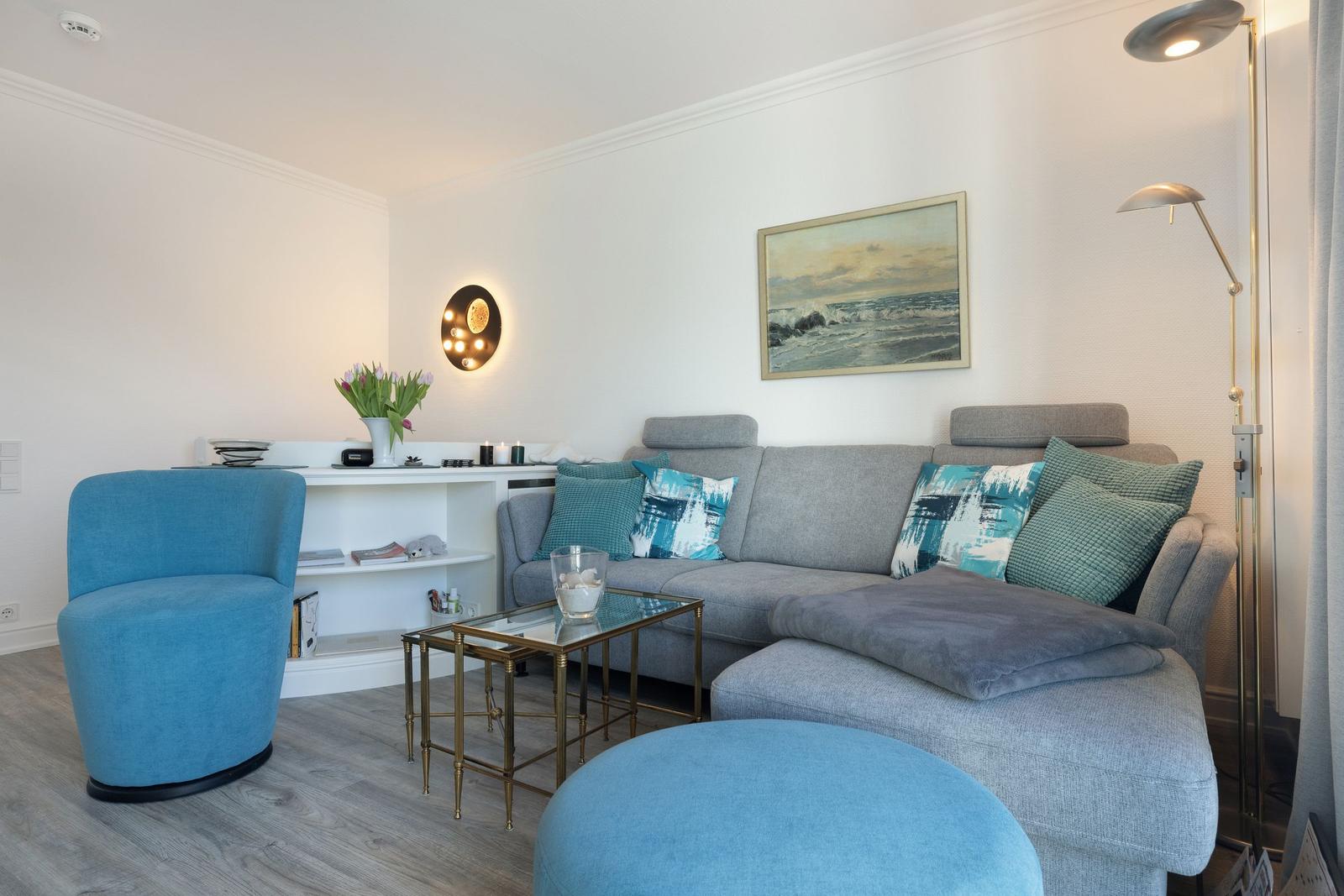 Living room with gray sofa, blue seating, and glass table.