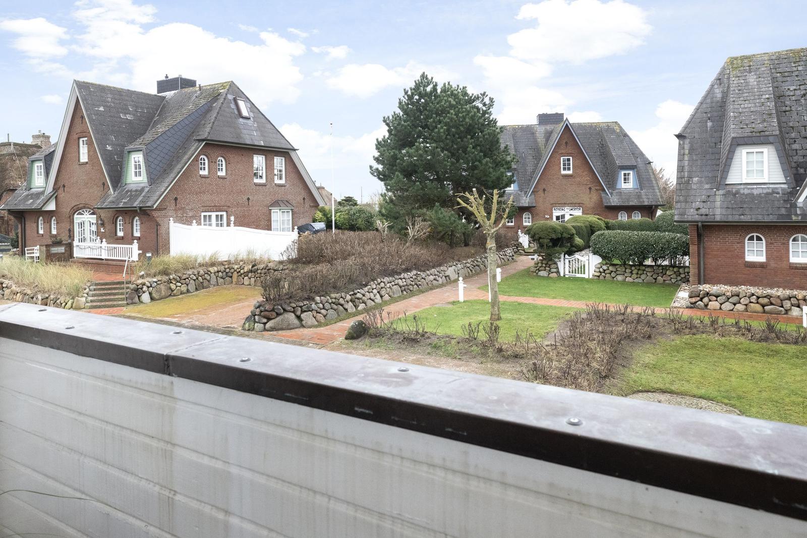 Rote Backsteinhäuser mit grauen Dächern und gepflegten Gärten.