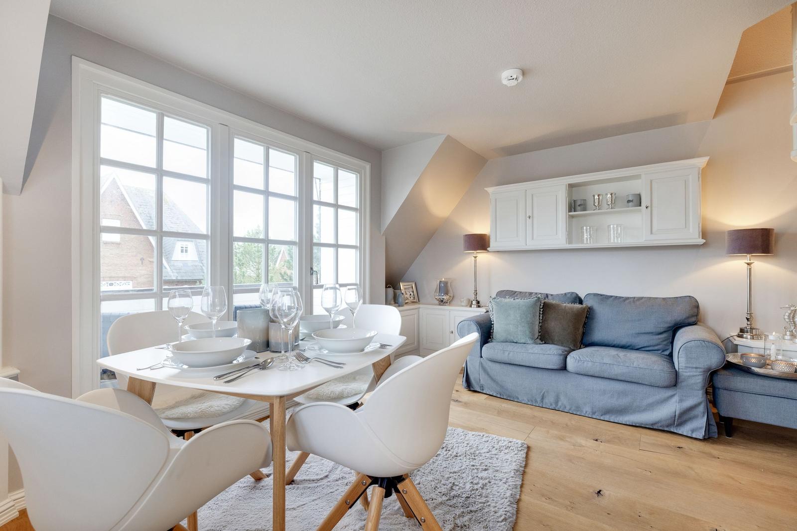 Essbereich mit Tisch und Stühlen, Wohnbereich mit Sofa und Schrank an der Wand.